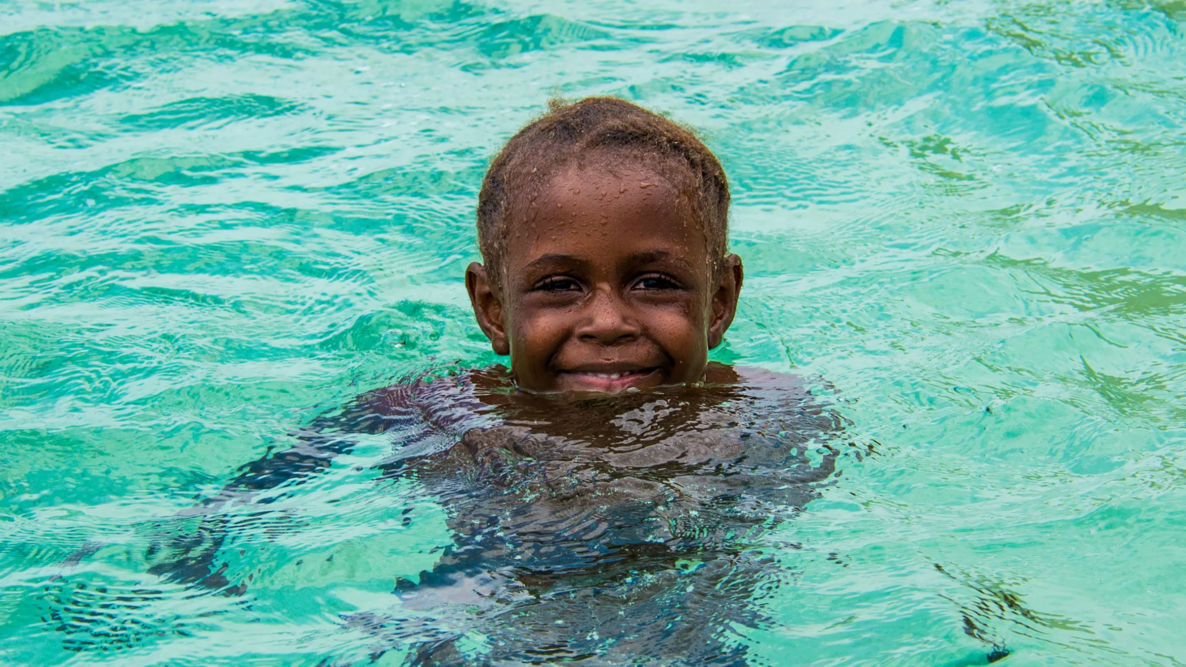 Niño de la etnia Garífuna disfruta de las cristalinas aguas de Cayos Cochinos
